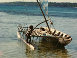 Child and outrigger sailboat, Panaete island, Louisiade Archipelago, Papua New Guinea photo